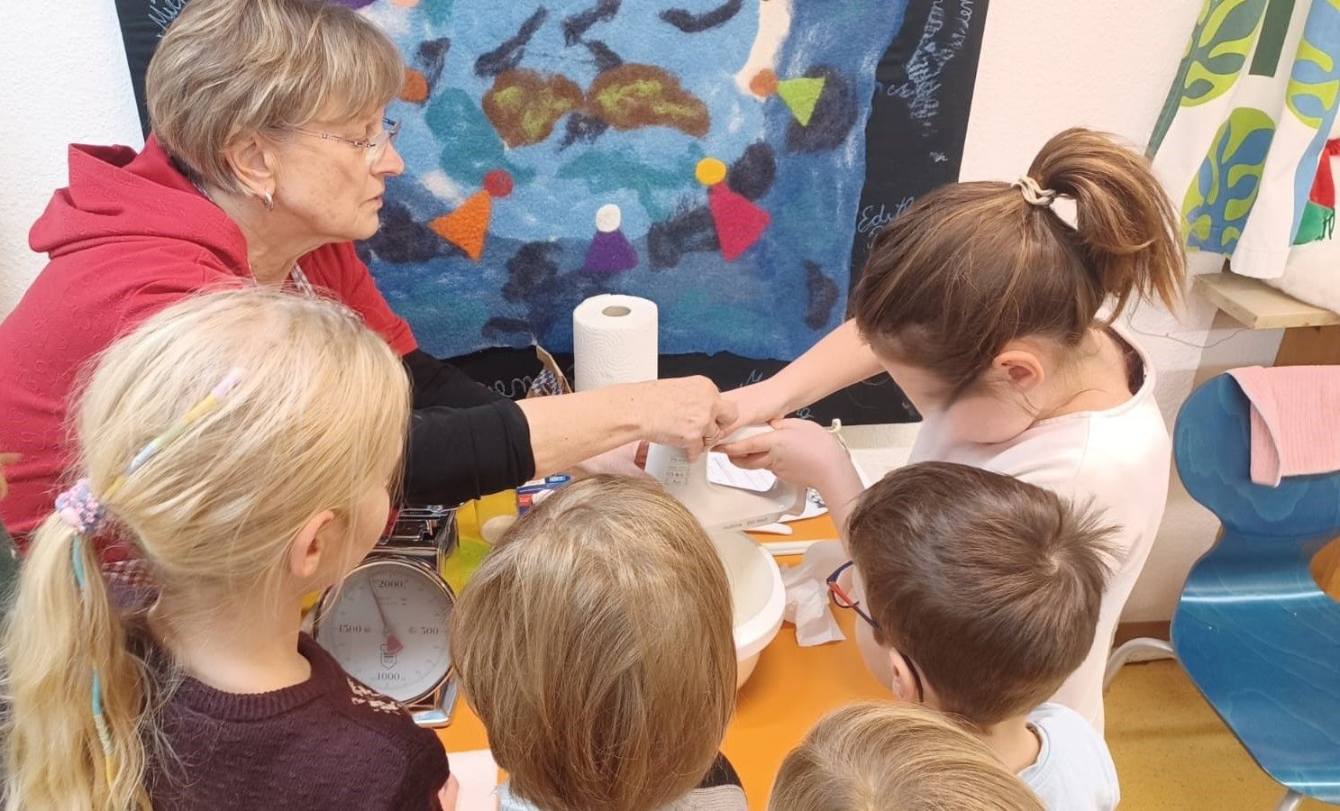 Kinder stehen um einen Tisch mit Waage und Teigschüssel