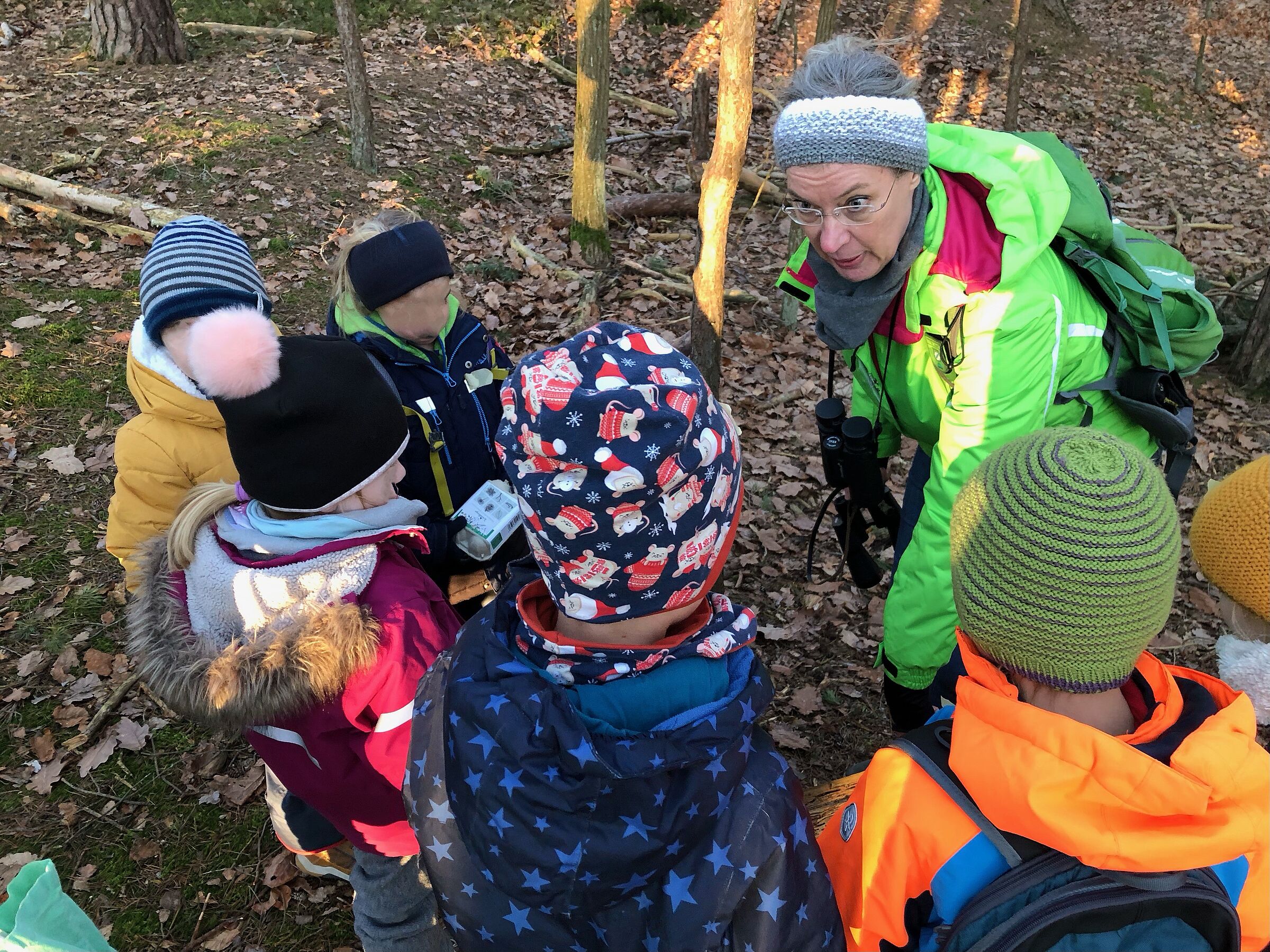 Kinder stehen im Wald im Kreis; Erwachsene Frau erklärt