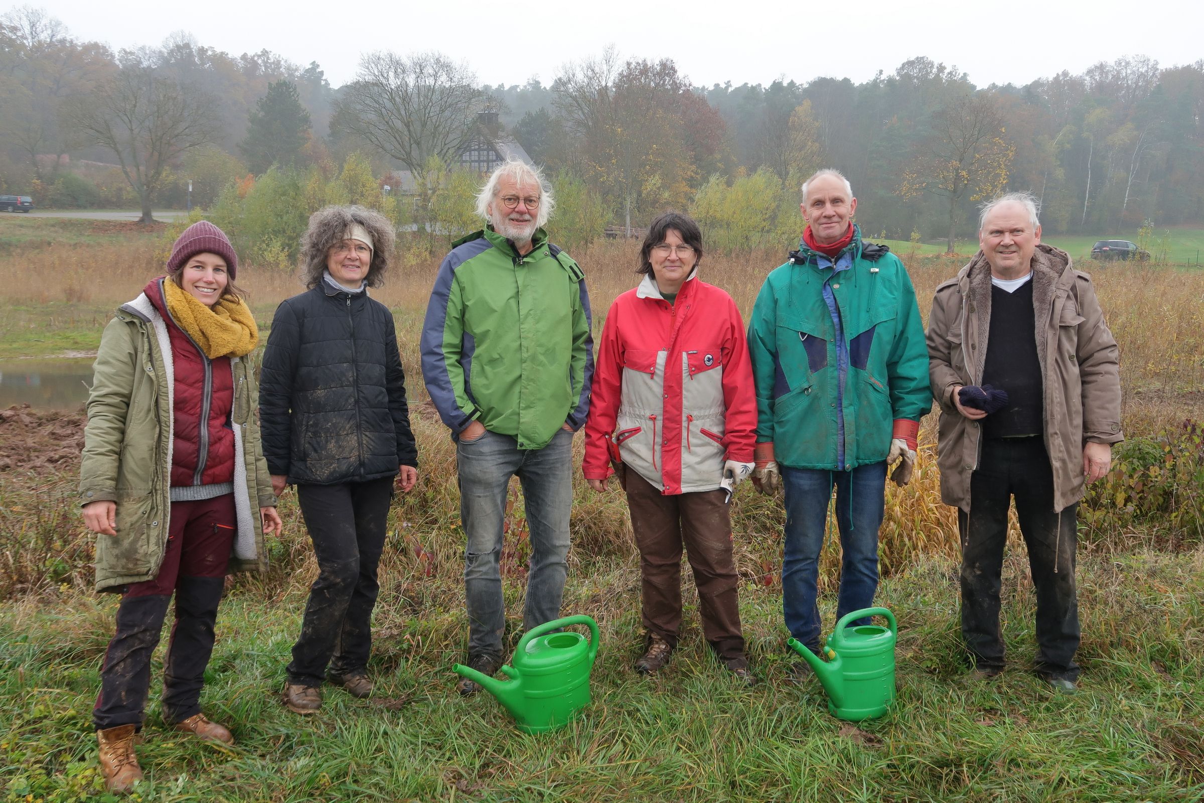 Erwachsene stehen mit schmutziger Kleidung auf einem Feld