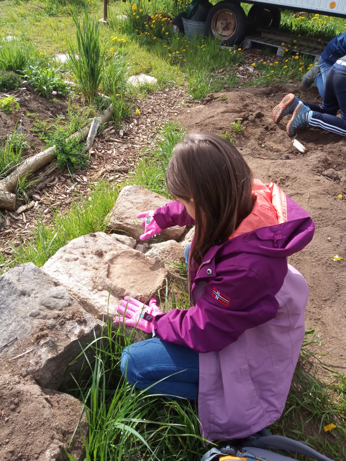 Kind spielt im Garten mit Sand
